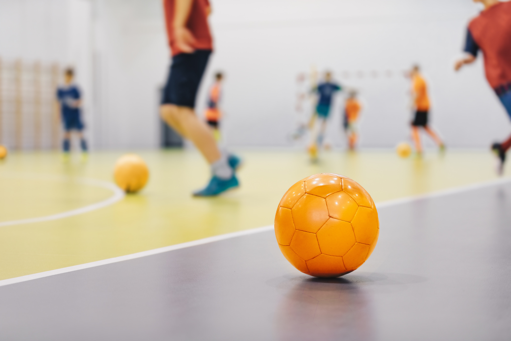 Orange Futsal Soccer Ball on Indoor Training Pitch. Young Player
